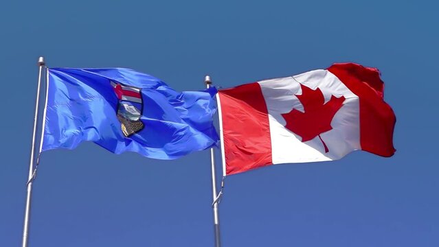 Slow motion of a waving Alberta and Canada flag on a blue sky.