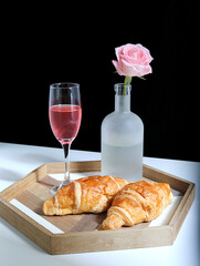 breakfast croissants, drinks and flowers and roses on a white table top