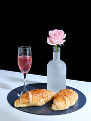 breakfast croissants, drinks and flowers and roses on a white table top