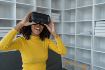 Stylish cheerful african american woman in vr headset spread arms and smiling while dancing and raising fingers in cyberspace. Metaverse vr future girl concept.