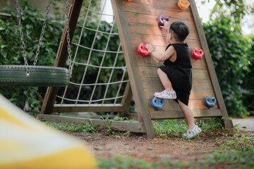 Fototapeta premium Asian little boy playing in the playground outdoor. Kids play on school or kindergarten yard. Healthy summer activity for children.