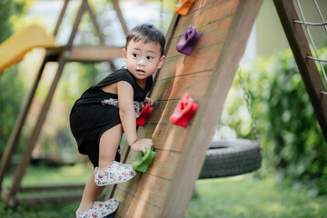 Asian little boy playing in the playground outdoor. Kids play on school or kindergarten yard. Healthy summer activity for children.