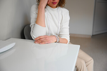 Unhappy woman touching hair sitting near the desk in the office. A pensive girl at a doctor's...