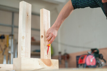 Caucasian man assembles the table with a screwdriver. Close-up of a carpenter's hands.
