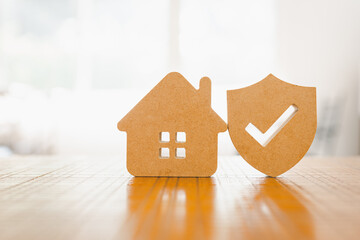 Wooden house model and real estate insurance ideas, and small shield icon. Housing insurance...