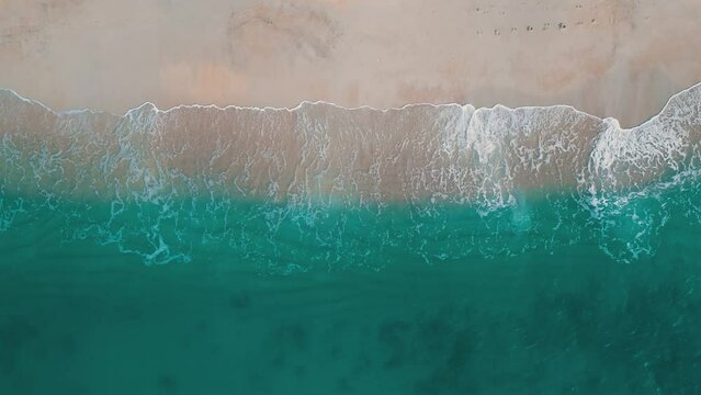 Aerial Top view of turquoise sea with beautiful waves at sunny day in summer. Drone shot of tropical seascape from the air of sea with azure water, sandy bottom. Aerial top view of sand beach. Summer