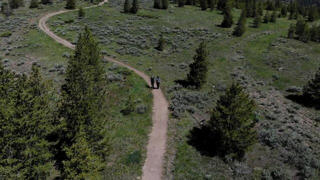 Drone footage of man and woman hiking on a trail.