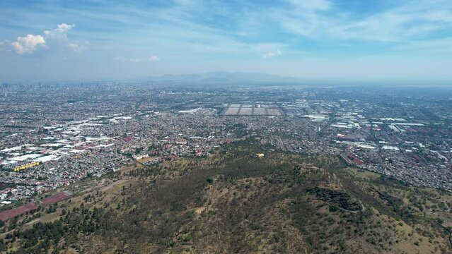 side drone shot of east Mexico city over cerro de la estrella in iztapalapa in mexico during a very polluted day