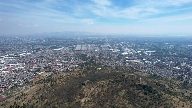 backwards drone shot of east Mexico city over cerro de la estrella in iztapalapa in mexico in a very polluted day