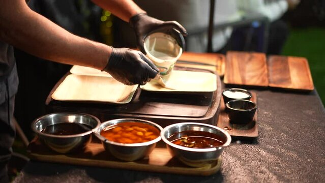 Professional food worker putting sauce on plates, serving bbq food