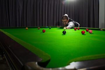 Asian man playing snooker, snooker club, Asian man playing snooker with selective focus on snooker...