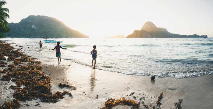 Kids watching and playing at the beach during sunset at the karst mountain island El Nido, Philippines