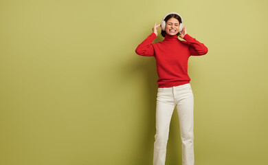 Fototapeta na wymiar Joyful young lady listening to favorite song and smiling in headphones