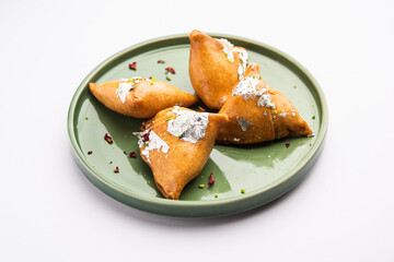 Indian sweet samosa is a Fried pastry soaked in sugar syrup filled with coconut, nuts and fruits