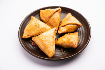 Indian sweet samosa is a Fried pastry soaked in sugar syrup filled with coconut, nuts and fruits