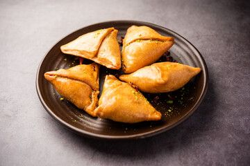 Indian sweet samosa is a Fried pastry soaked in sugar syrup filled with coconut, nuts and fruits