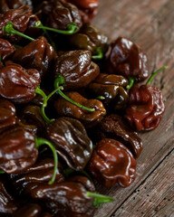 Lots of hot chocolate habanero peppers. Bunch of brown peppers. Harvest of peppers. Mexican ripe hot pepper. Bright spice. Spicy food. Wooden background. Soft focus. Top view.