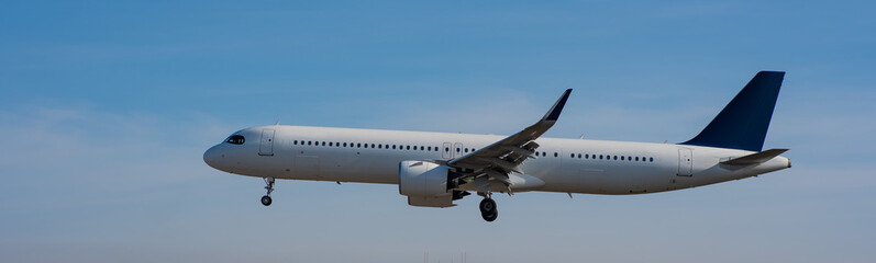 Side view of an airplane landing against a blue sky. Widescreen. 