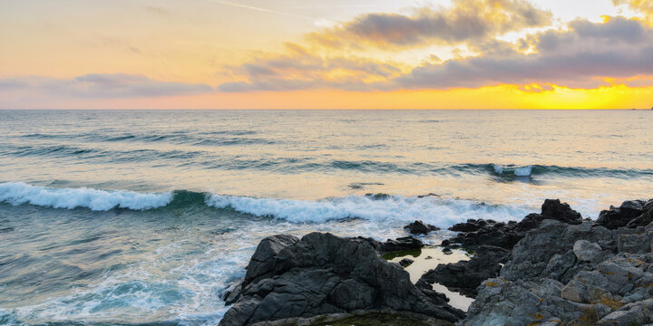 dramatic sunrise at the sea. rocky coast and cloudy sky