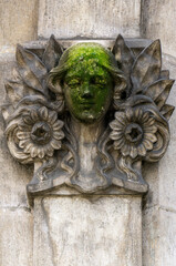 Obraz na płótnie Canvas Bas-relief - mascaron girl's face surrounded by flowers and leaves