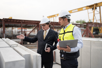 Portrait two caucasian engineer man working with notebook computer at precast site work	