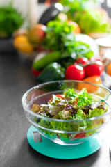 A closeup of a fresh healthy salad on a kitchen scale