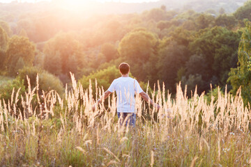 Fototapeta na wymiar young man alone in the middle of a field at sunset in summer