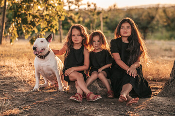 three sisters sit under a tree in black dresses in nature