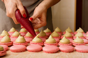 The confectioner puts the filling into the macarons