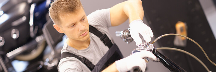 Auto mechanic repairs motorcycle fork in workshop. Motorcycle repair and maintenance concept