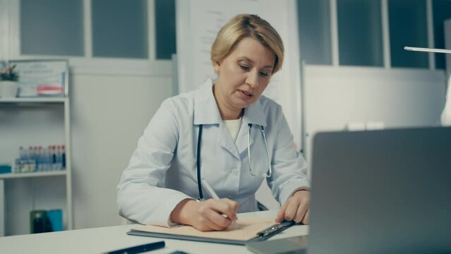 Family doctor consulting patient online, writing medicine prescription on paper