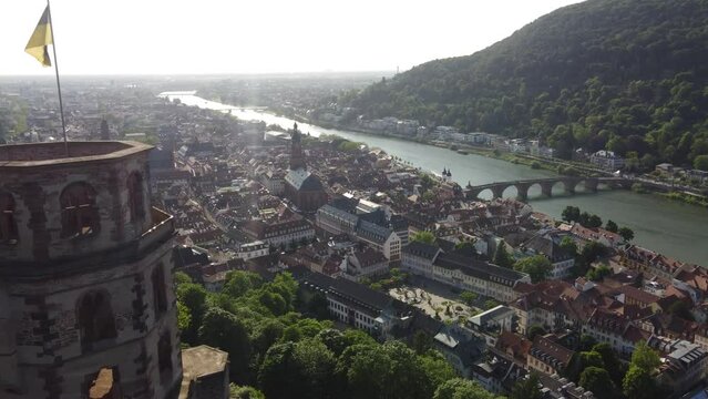 Heidelberg, Germany city Cinematic aerial, flying past Bell Tower of heidelberger Castle revealing riverfront downtown at summer sunset.