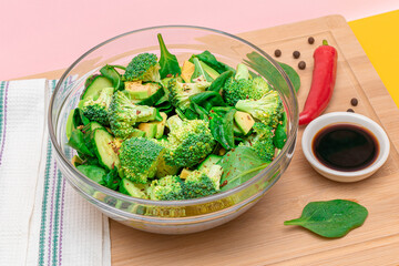 Fresh Green Salad of Avocado, Broccoli, Spinach and Cucumber with Soy Sauce and Red Hot Pepper on Wooden Cutting Board. Vegan Salad. Vegetarian Culture. Raw Food. Healthy Eating and Vegetable Diet