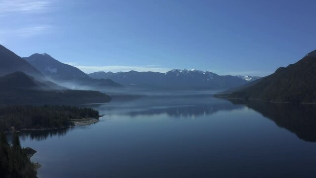 Transcendent Reflections: Smoke's Luminous Veil upon Slocan Lake's Crystal Waters