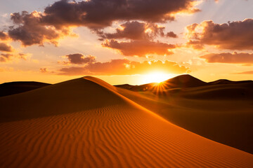 Obraz na płótnie Canvas Sunset over the sand dunes in the desert. Arid landscape of the Sahara desert.