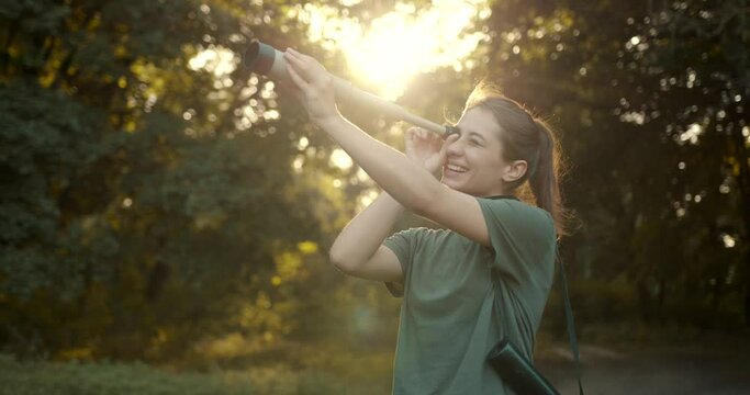 Hiker standing in the forest and looking through telescope