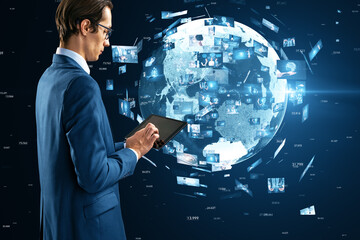 Side view of young european businessman using tablet with creative globe with telecommunication...