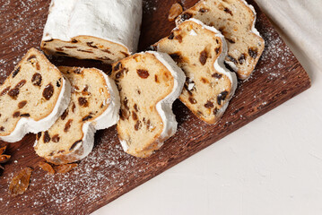 Stollen sliced on pieces, on wooden board, traditional German winter holiday bakery, cake with raisins and sugar powder