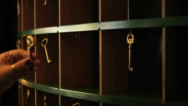 Female Hand Takes Old Room Key from Vintage Style Hotel Reception Rack, 4K Slowmotion Cinematic Travel Mood Concept Footage, Thailand.