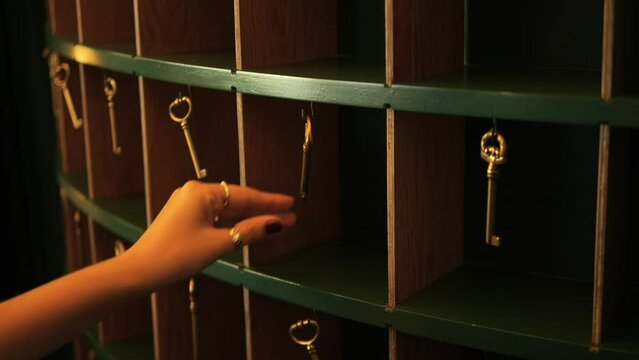 Female Hand Hangs Old Room Key on Vintage Style Hotel Reception Rack, 4K Slowmotion Cinematic Travel Mood Concept Footage, Thailand.
