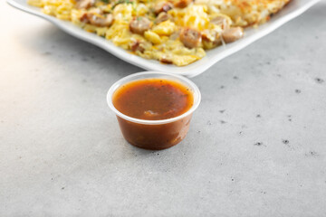 A view of a plastic condiment cup of red salsa.