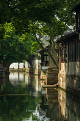 landscape of a Chinese ancient town with river, wooden houses and boat.