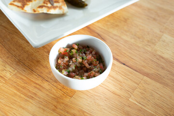 A view of a condiment cup of pico de gallo salsa.