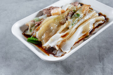 A view of a plate of beef and shrimp rice noodle roll.