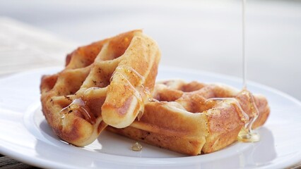 Close up Honey pouring on waffles. Soft waffles with natural honey, Waffles on white plate. Breakfast with Belgian waffles
