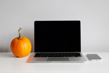 Laptop, phone and orange pumpkin on table