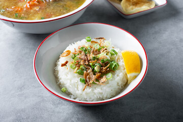 A view of a bowl of steamed white rice, topped with fried onions and scallions.