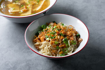 A view of a bowl of Indonesian egg noodles, next to a bowl of bakso tahu.