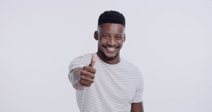 Face, smile and thumbs up of black man in studio isolated on a white background. Portrait, like hand gesture and African male person with emoji for agreement, success or review, vote and mockup goal.