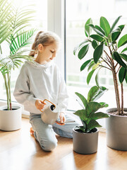 Little girl watering houseplants in her house.